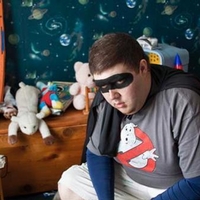 Boy wearing a Ghostbusters t-shirt wearing black caper mask and cape